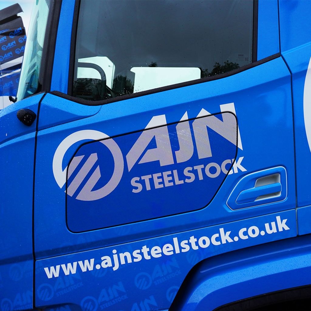 A close-up of a vehicle wrap, showing the high-quality application and precision-cut detail of the AJN Steelstock branding on a truck door by Indigo Ross