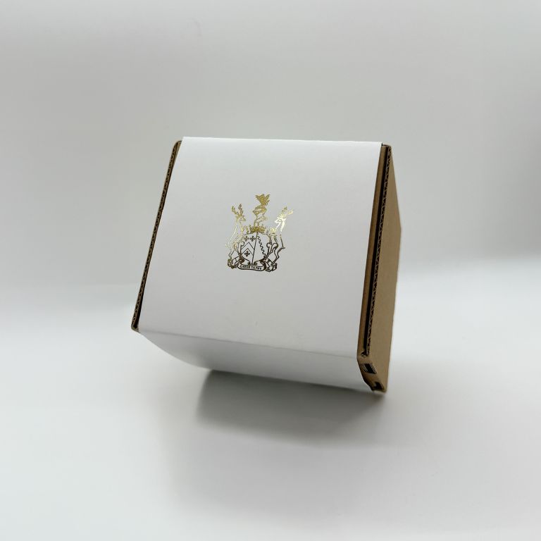 A custom box with a white belly band featuring a gold foil logo. Premium print finishing by Indigo Ross