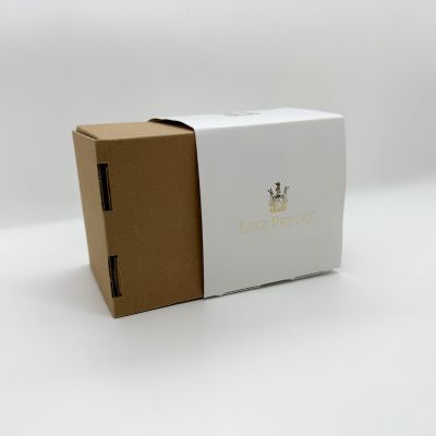 A custom box for the Leez Priory wedding venue, featuring a white sleeve with a gold foil crest over a brown fluted box. Luxury packaging by Indigo Ross.