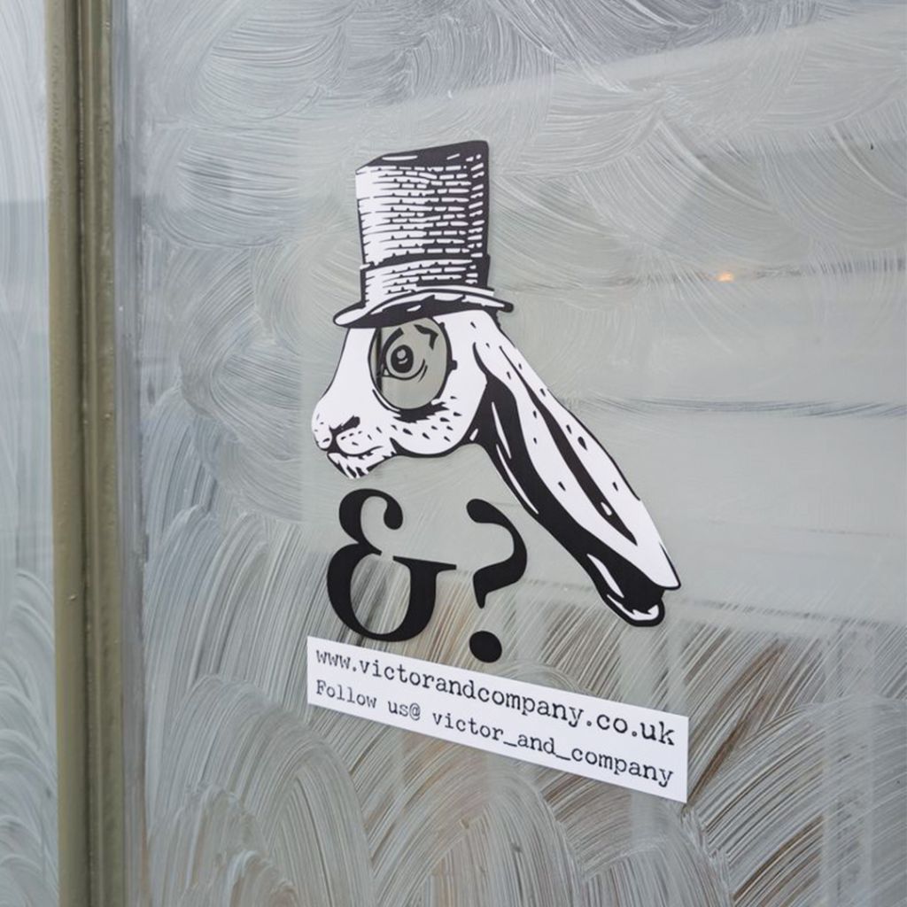 Close-up of an interactive "spy hole" window graphic featuring the Victor the Hare character with a monocle, applied to a frosted shop window.