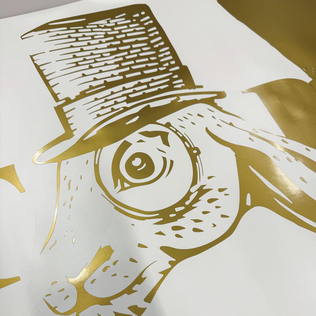 Behind-the-scenes shot of precision-cut gold vinyl graphics for the Victor & Company logo.